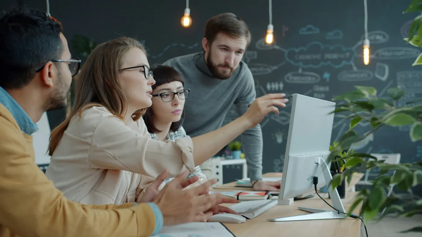 Equipe reunida diante de um monitor, analisando dados juntos
